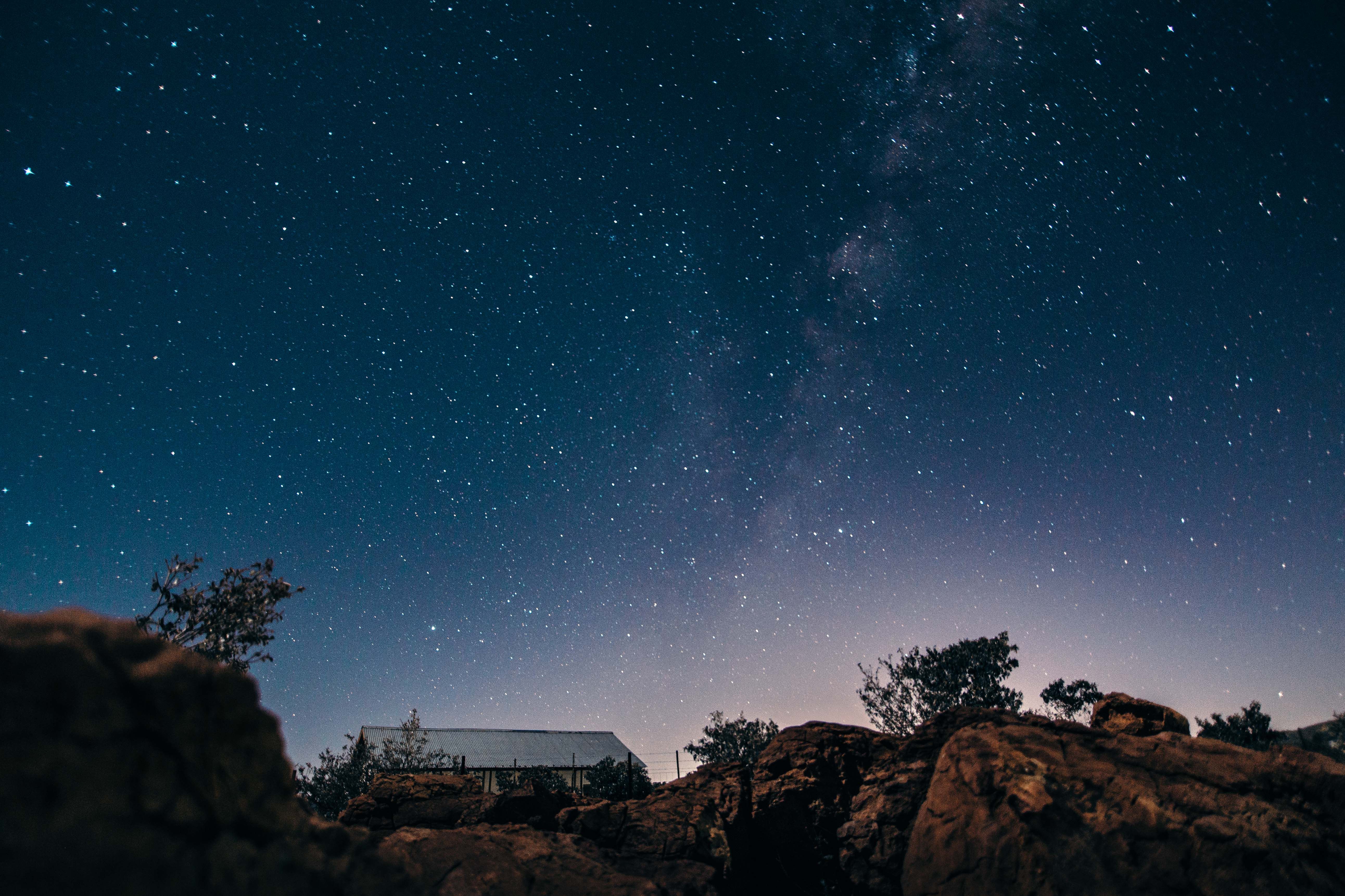 星光夜空迷人地笼罩在乡村房屋和崎岖的景观之上