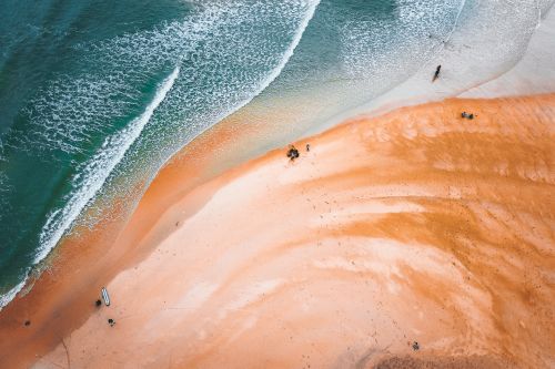 Free Top view of foamy ocean waves rolling into sandy shore with silhouettes of people Stock Photo