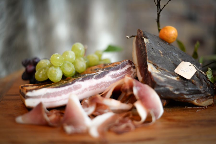 Sliced cured ham with grapes on a rustic board