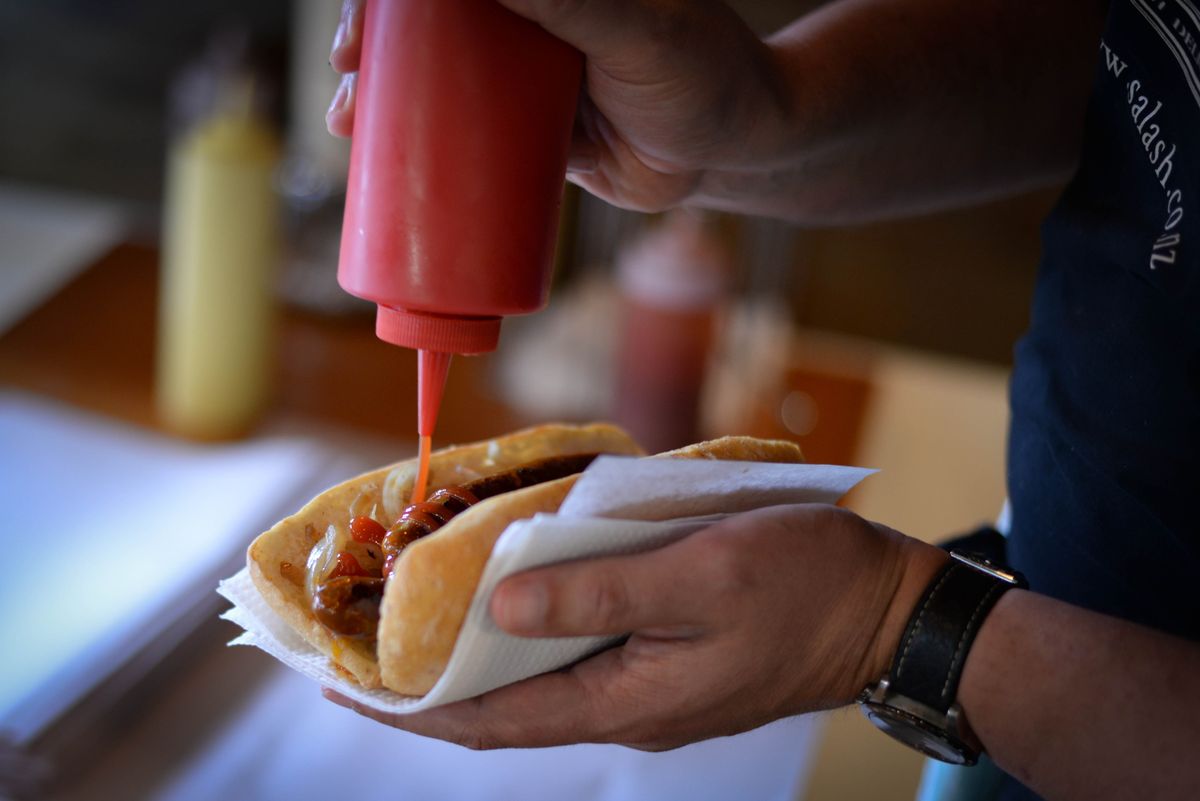 Man serving a hot dog with ketchup at a cafe