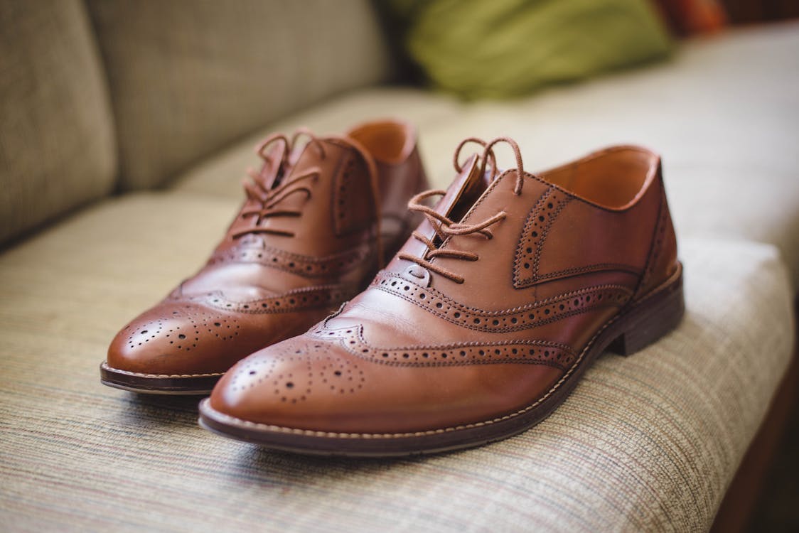 Free Elegant brown pair of leather shoes for men placed on gray surface at home Stock Photo