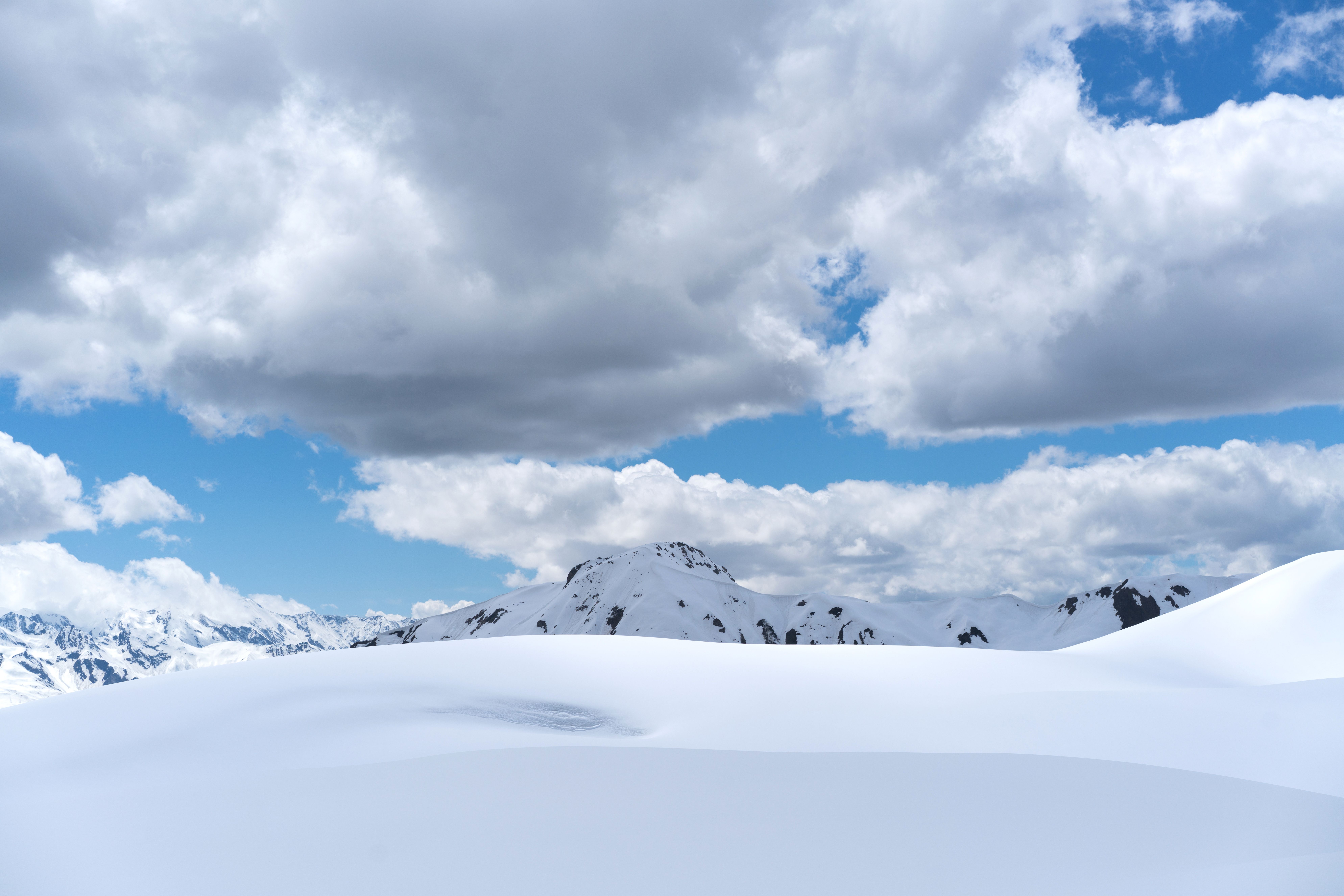 Snow Covered Mountain Under White Clouds and Blue Sky · Free Stock Photo