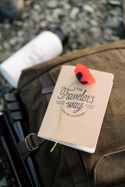 A traveler's journal with a red poppy on a backpack, ready for outdoor adventures.