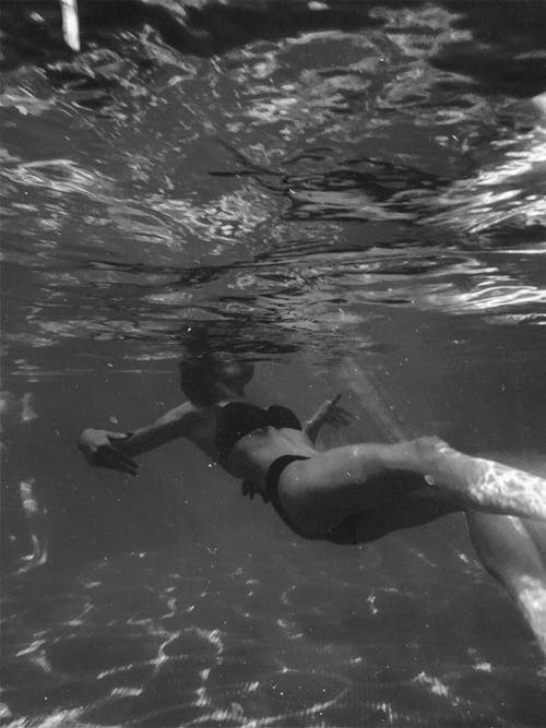 Grayscale Photo of Woman Swimming