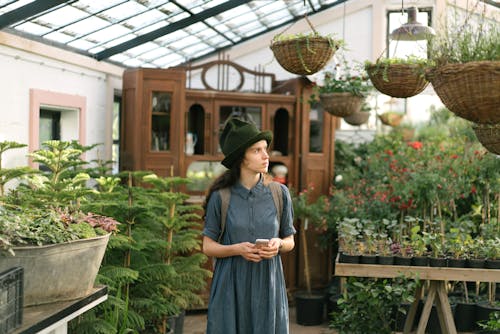 Woman in Blue Dress Standing Near Green Plants