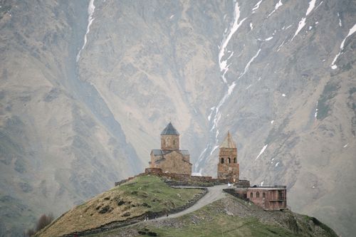 Free A historical church stands against a majestic mountain backdrop, perfect for travel inspiration. Stock Photo