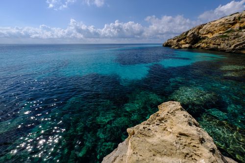 Free Beautiful coastal scene showcasing clear blue waters and rocky formations under a clear sky. Stock Photo