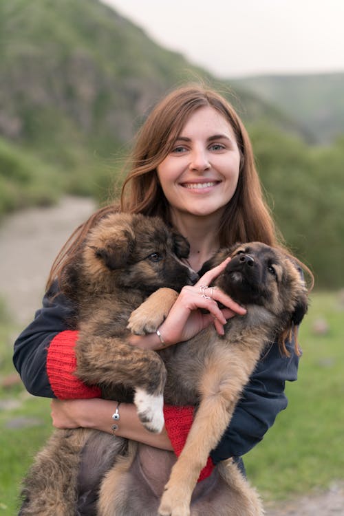 Woman Smiling While Holding Brown and Black German Shepherd