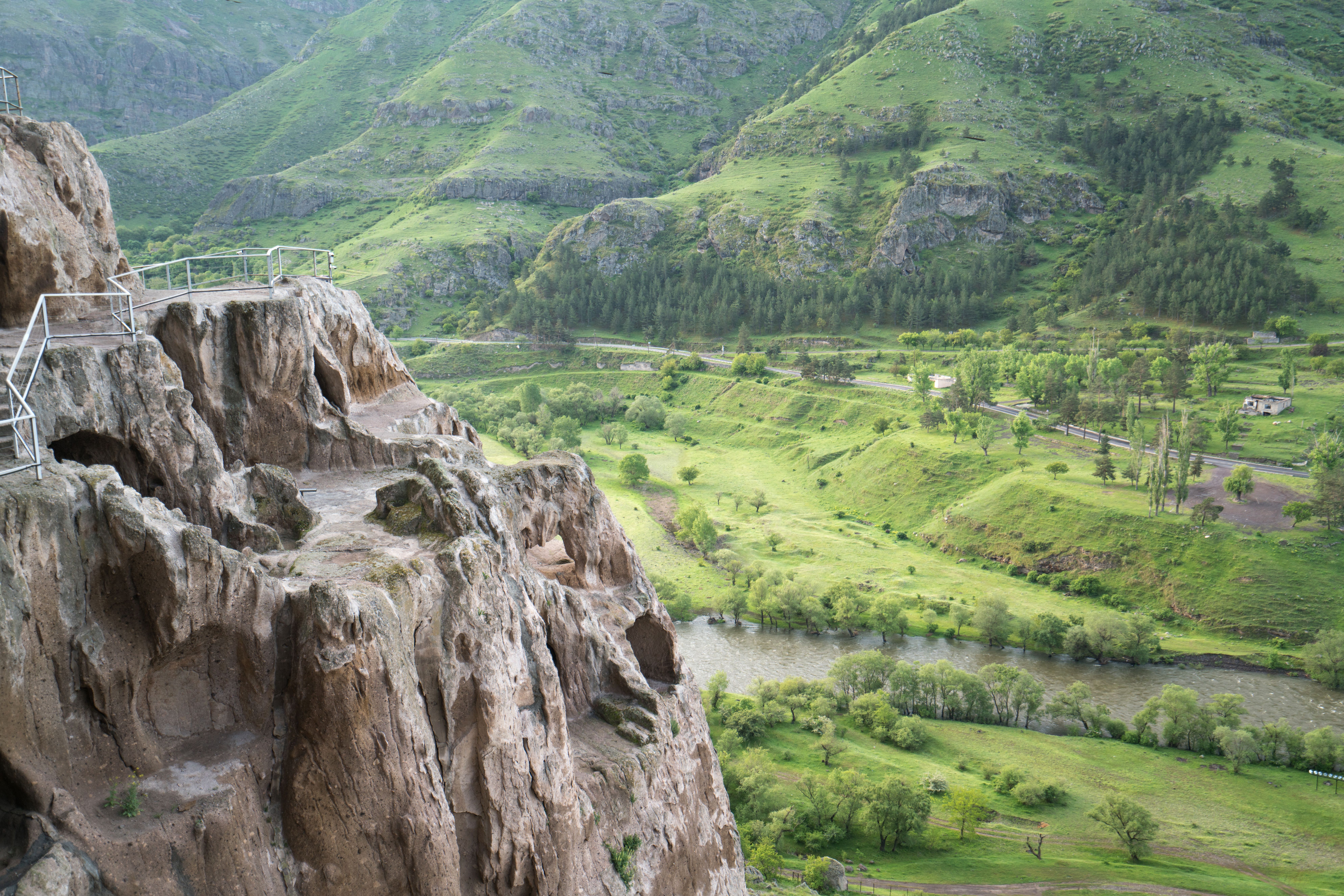 Breathtaking view of lush green mountains and rocky cliffs with a flowing river below.