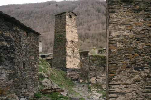 Free A historic stone tower amidst medieval structures in a mountainous landscape. Stock Photo