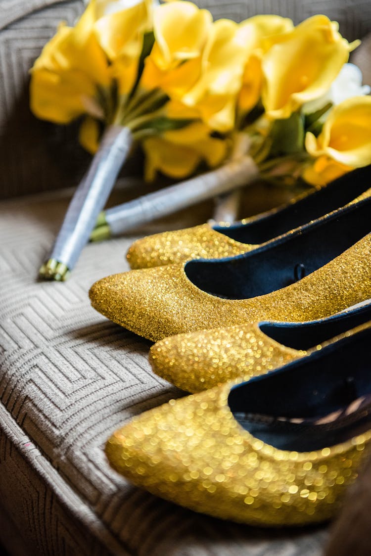 Stylish Golden Shoes And Yellow Bouquets On Sofa