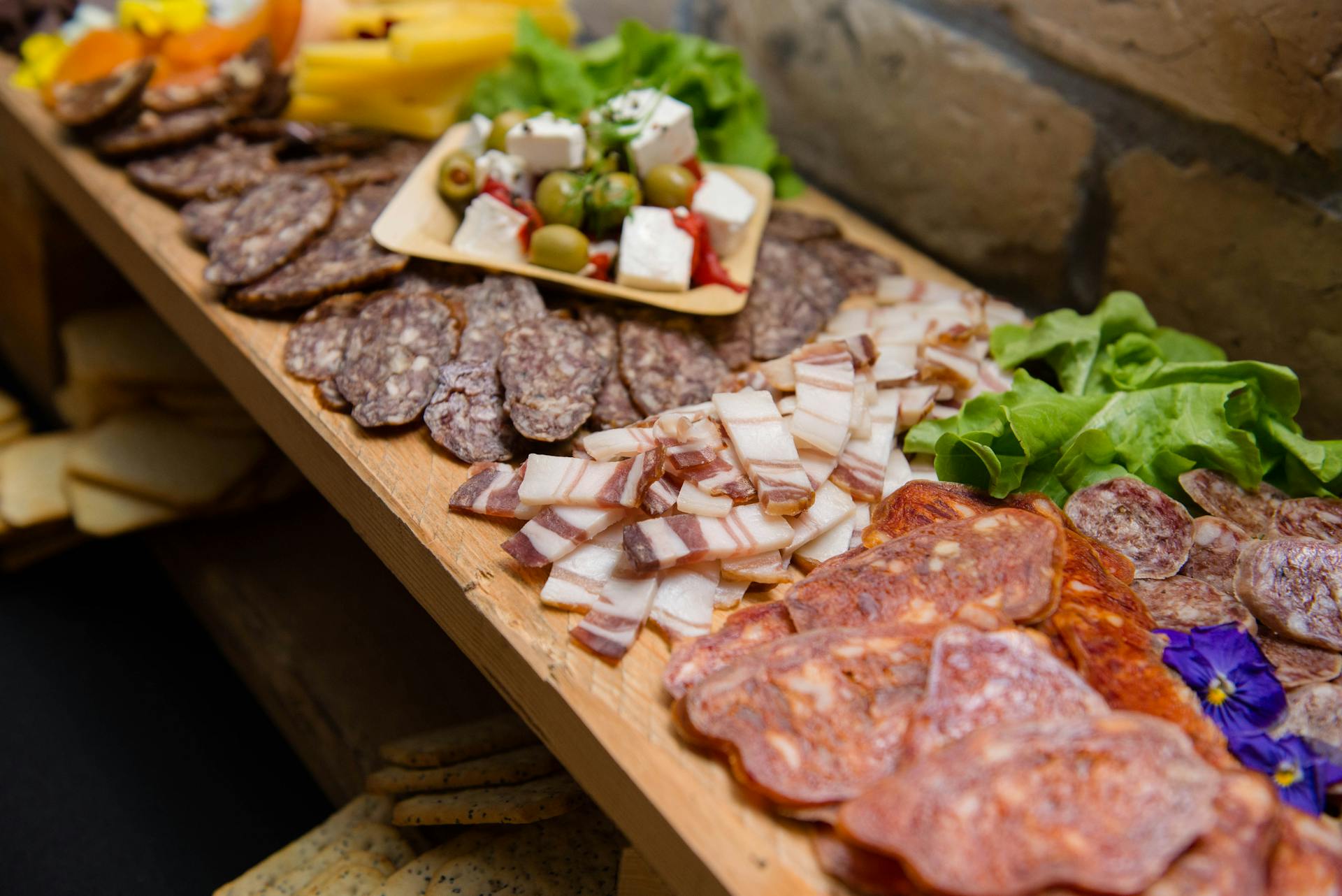 High angle appetizing sliced cured pork fat and smoked sausages served on sideboard with cheese and olives during buffet catering