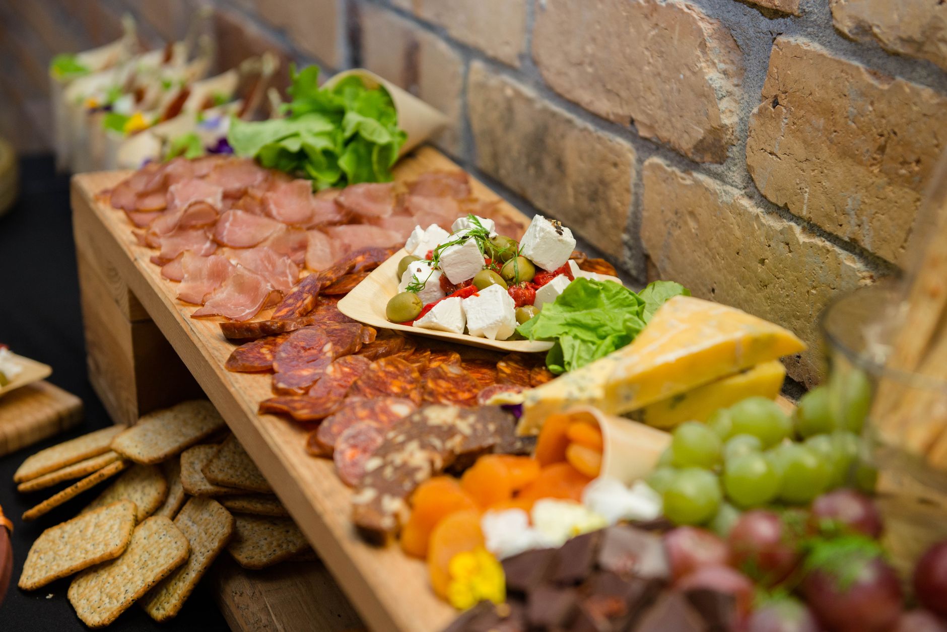High angle assorted palatable appetizers including sliced meat sausages cheese and grapes served on sideboard