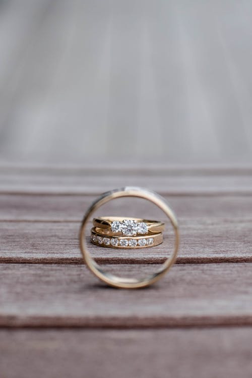Composition of elegant wedding rings with diamonds on wooden surface