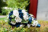 Bouquet of white and blue flowers and green leaves on grass in daylight on blurred background
