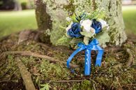 Little bunch of mixed blue and white flowers decorated with bow and ribbon beside moss and sticks