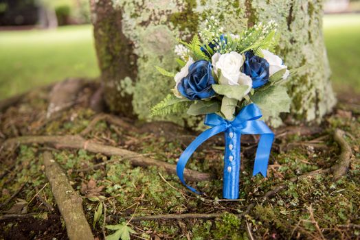 Little bunch of mixed blue and white flowers decorated with bow and ribbon beside moss and sticks