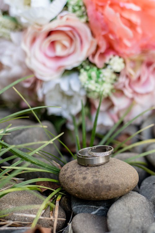 Bright flower bouquet near rings on stones