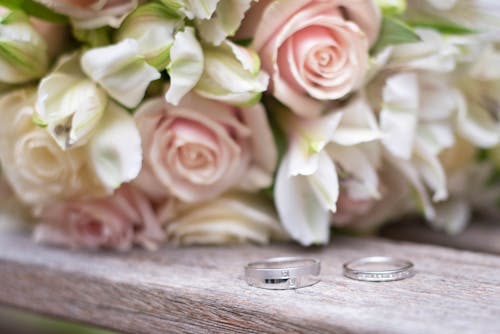 Closeup of colorful blossoming flower bouquets with gentle petals near shiny rings with precious stones on wedding day