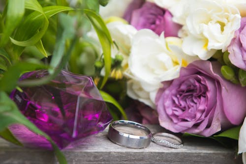 Silver rings near bright blossoming flowers on wedding day
