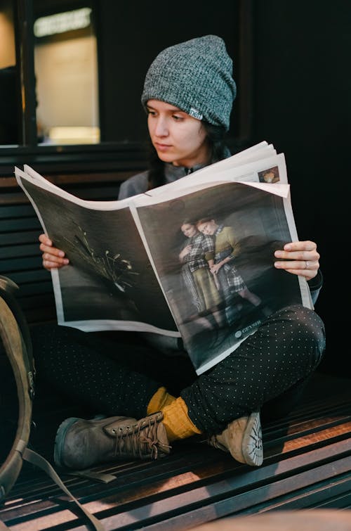 Photo of Woman Sitting While Reading Newspaper