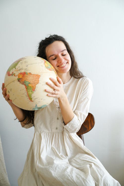 Woman in White Dress Holding Globe