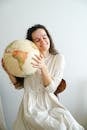 Woman in White Dress Holding Globe