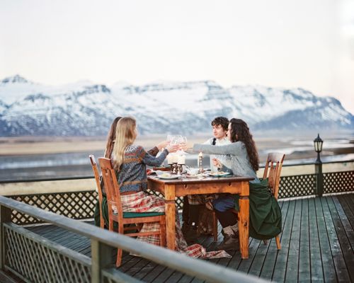 Free Friends enjoying a meal at an outdoor table with stunning mountain views. Stock Photo