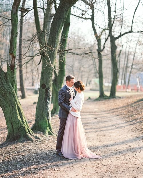 Free A bride and groom embrace romantically in a serene forest path, bathed in soft daylight. Stock Photo