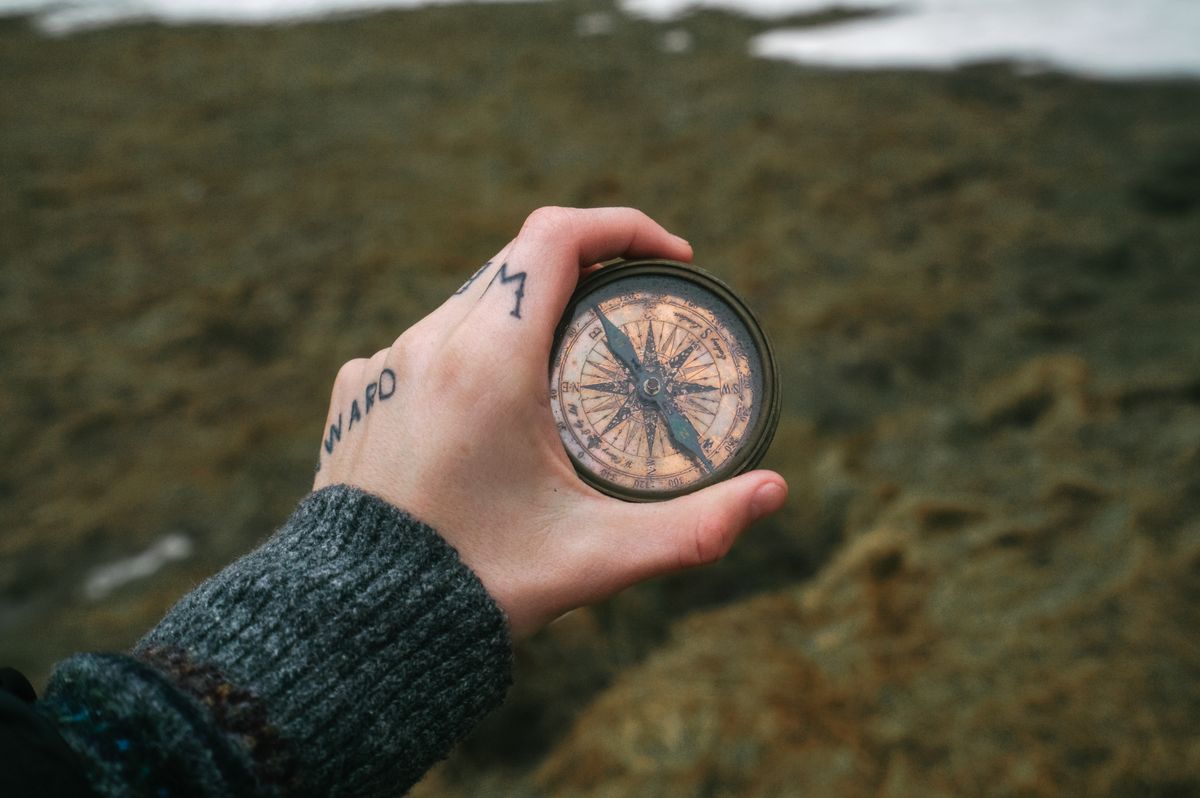 A hand holding an antique brass compass — photo by ArtHouse Studio on Pexels