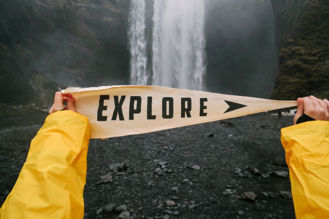 Hands Holding Explore Sign against Waterfall · Free Stock Photo