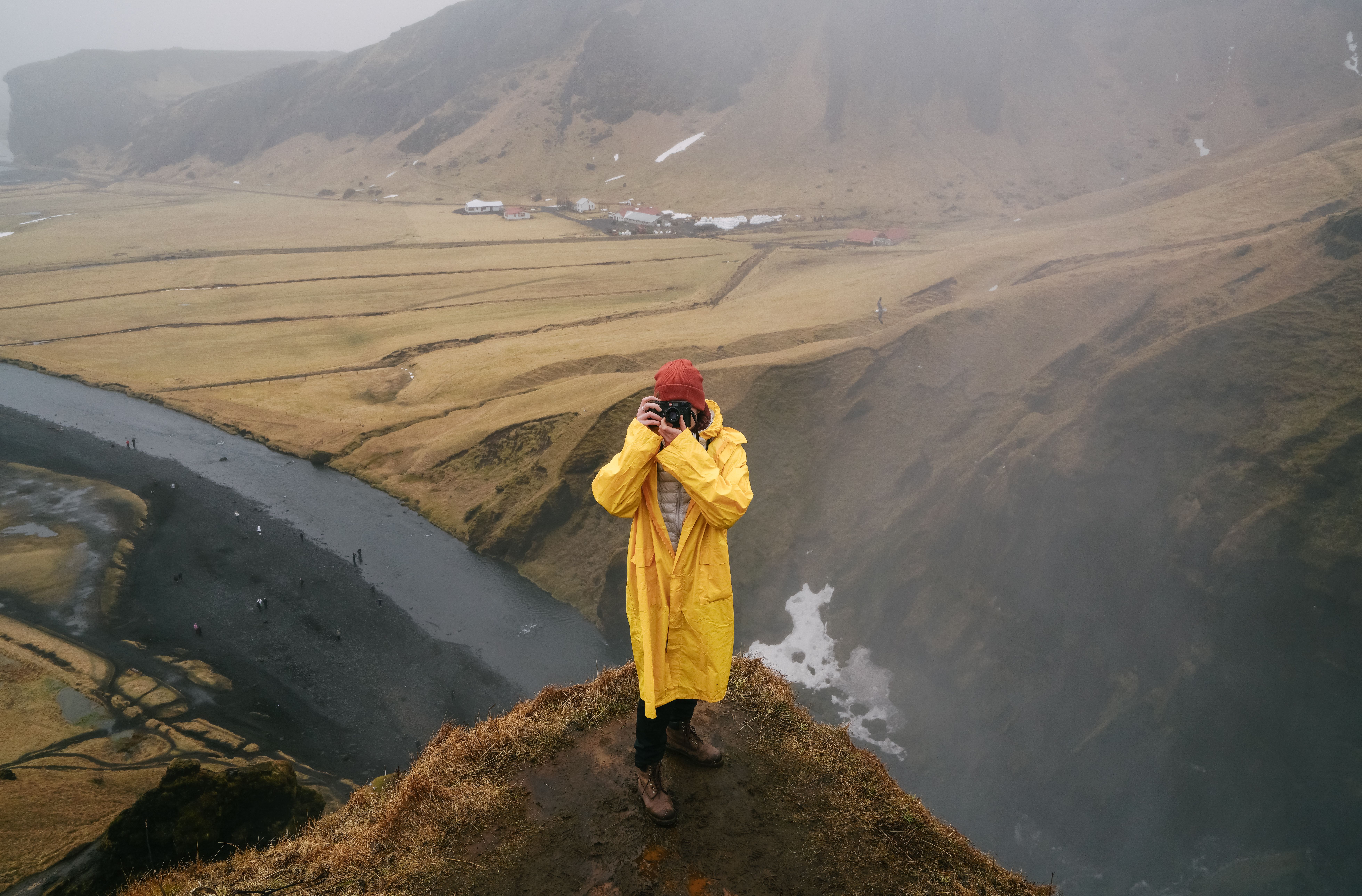 摄影师身穿黄色雨衣，从悬崖上捕捉到了朦胧的山间景观
