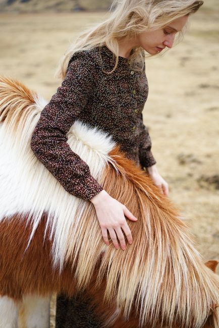 A woman gently embraces a pony in a tranquil outdoor scene, showcasing natural bond.