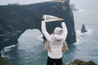 Woman Holding Sign on Sea Shore