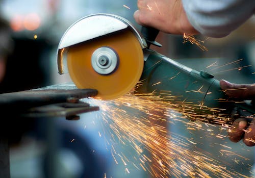 Crop blacksmith cutting metal with grinder