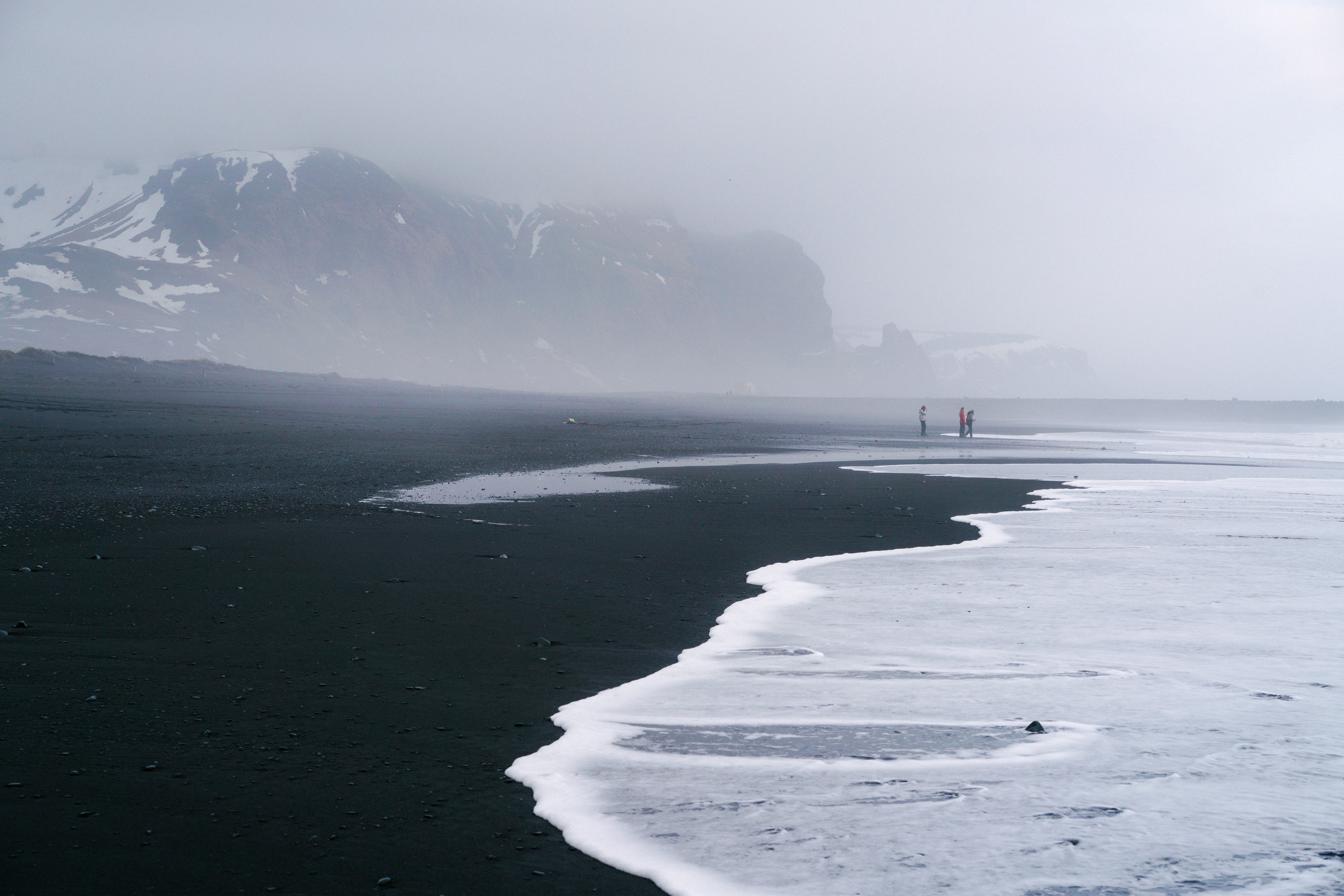 Misty coastal scene with black sand, waves, and distant mountains.. misty, coastal, scene