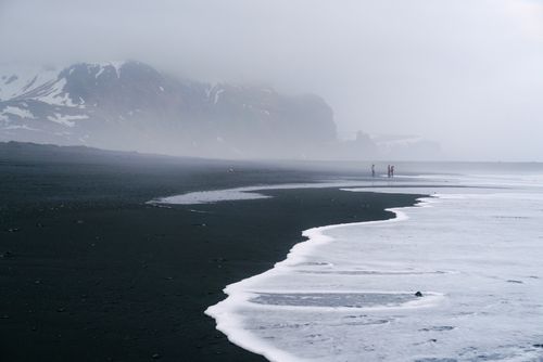 Free Misty coastal scene with black sand, waves, and distant mountains. Stock Photo
