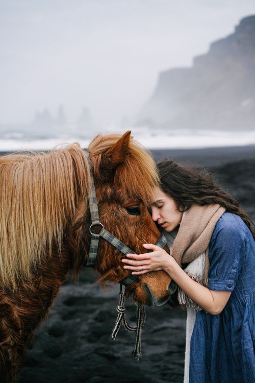 Free A woman lovingly embraces a pony on a misty beach, showcasing a serene connection. Stock Photo