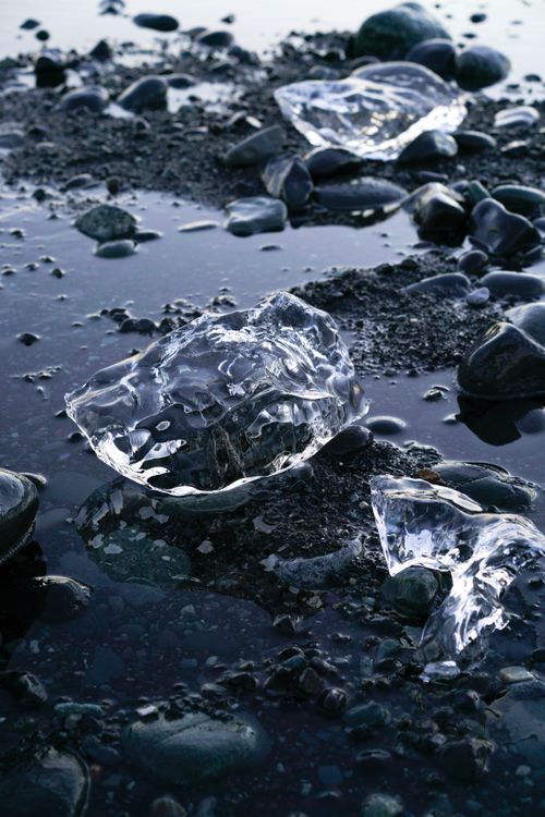 Free Serene close-up of ice chunks on a rocky shoreline, capturing the cold beauty of nature. Stock Photo