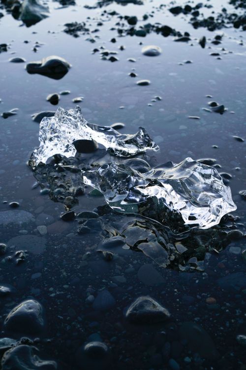 Free Close-up of clear ice blocks on a reflective rocky surface, highlighting winter's cold beauty. Stock Photo