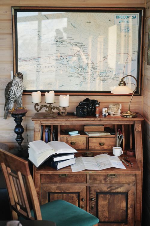 Free A rustic study space featuring open books, a detailed map, and vintage decor including a lamp and candles. Stock Photo