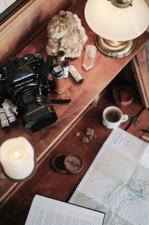 Free A cozy workspace featuring a vintage camera, travel map, and desk items in a warm setting. Stock Photo