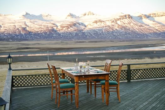 Elegant table setting on a wooden deck with stunning snow-capped mountain views.