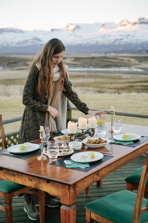 Free A woman sets a table for a meal outdoors with breathtaking mountain views. Stock Photo