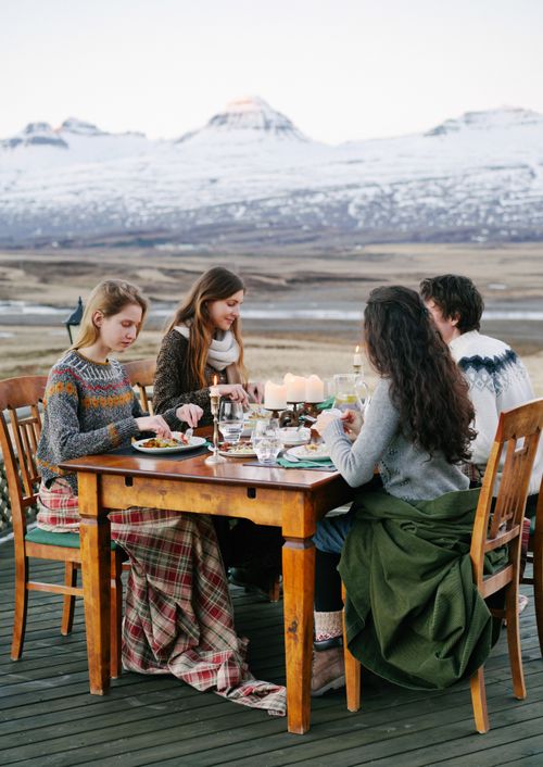 Free Friends enjoying a cozy outdoor dinner with a snowy mountain backdrop. Stock Photo