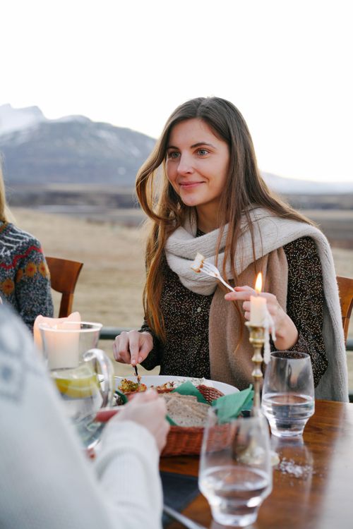 Free Woman dining outdoors with scenic mountain backdrop and candlelight ambiance. Stock Photo