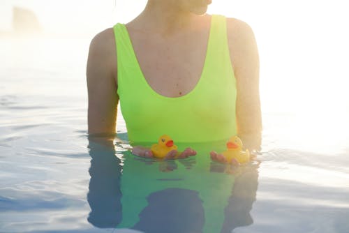 Free Woman in Green Tank Top With Yellow and Blue Rubber Duck on Water Stock Photo