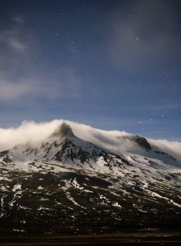 星光灿烂的夜空下，雪山笼罩在云层中，非常适合自然爱好者