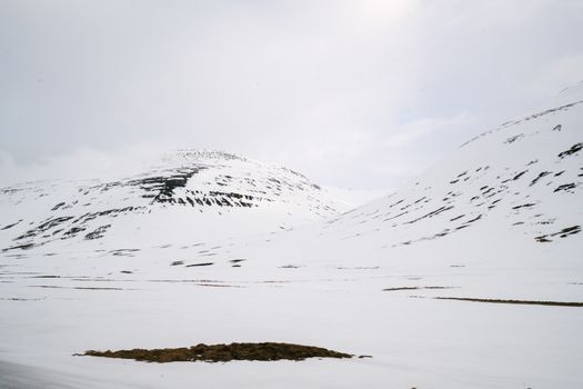 Vast snow-covered mountains under a cloudy winter sky, serene and untouched.