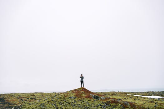 A solitary photographer stands atop a hill, capturing the vast barren landscape.
